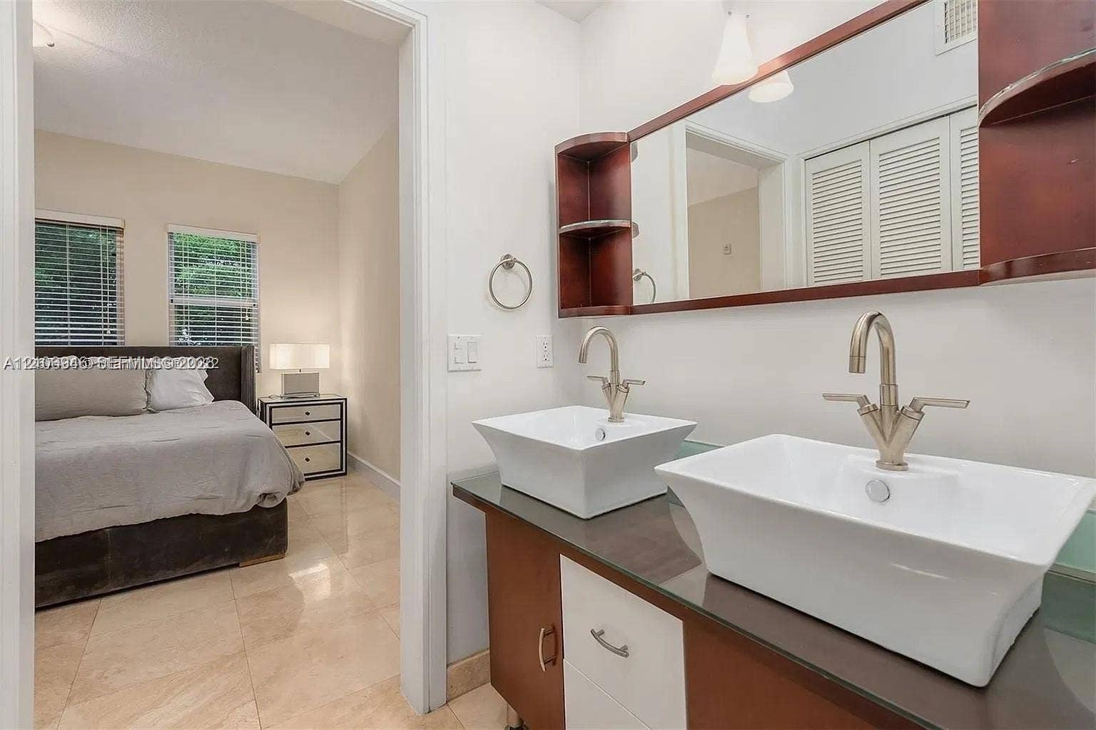 Vanity featuring a dark-finish base with integrated storage, a dark countertop, dual rectangular vessel sinks, and a wall-mounted wood-trim mirror with side shelving