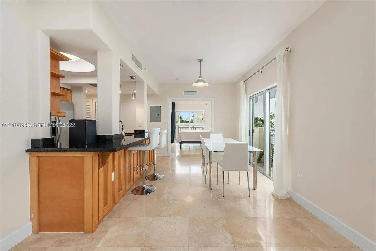 Kitchen featuring natural wood cabinetry, dark stone countertops, stone tile flooring, and integrated pendant lighting