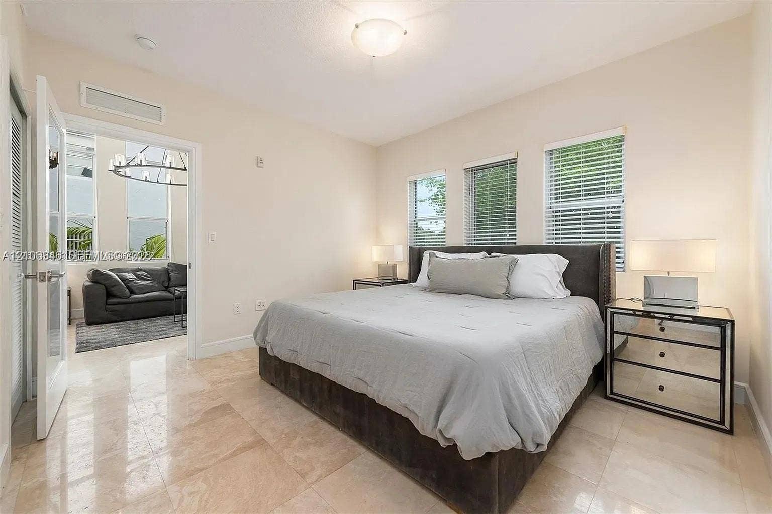 Neutral-toned room featuring large-format polished stone flooring, three windows with horizontal blinds, and a semi-flush mount ceiling fixture