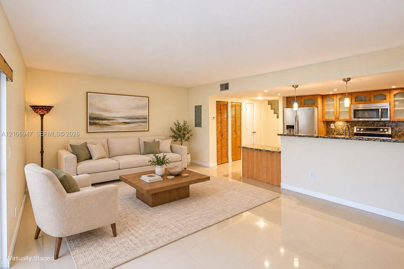 Open-concept living space featuring high-gloss tile flooring, stone-surfaced kitchen breakfast bar, stainless steel appliances, wood cabinetry with glass-front uppers, and recessed lighting
