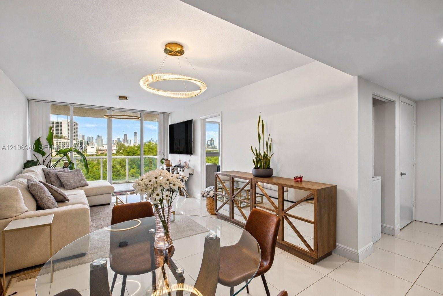 Large floor-to-ceiling windows, polished tile flooring, contemporary circular LED light fixtures, and glass-paneled balcony railing