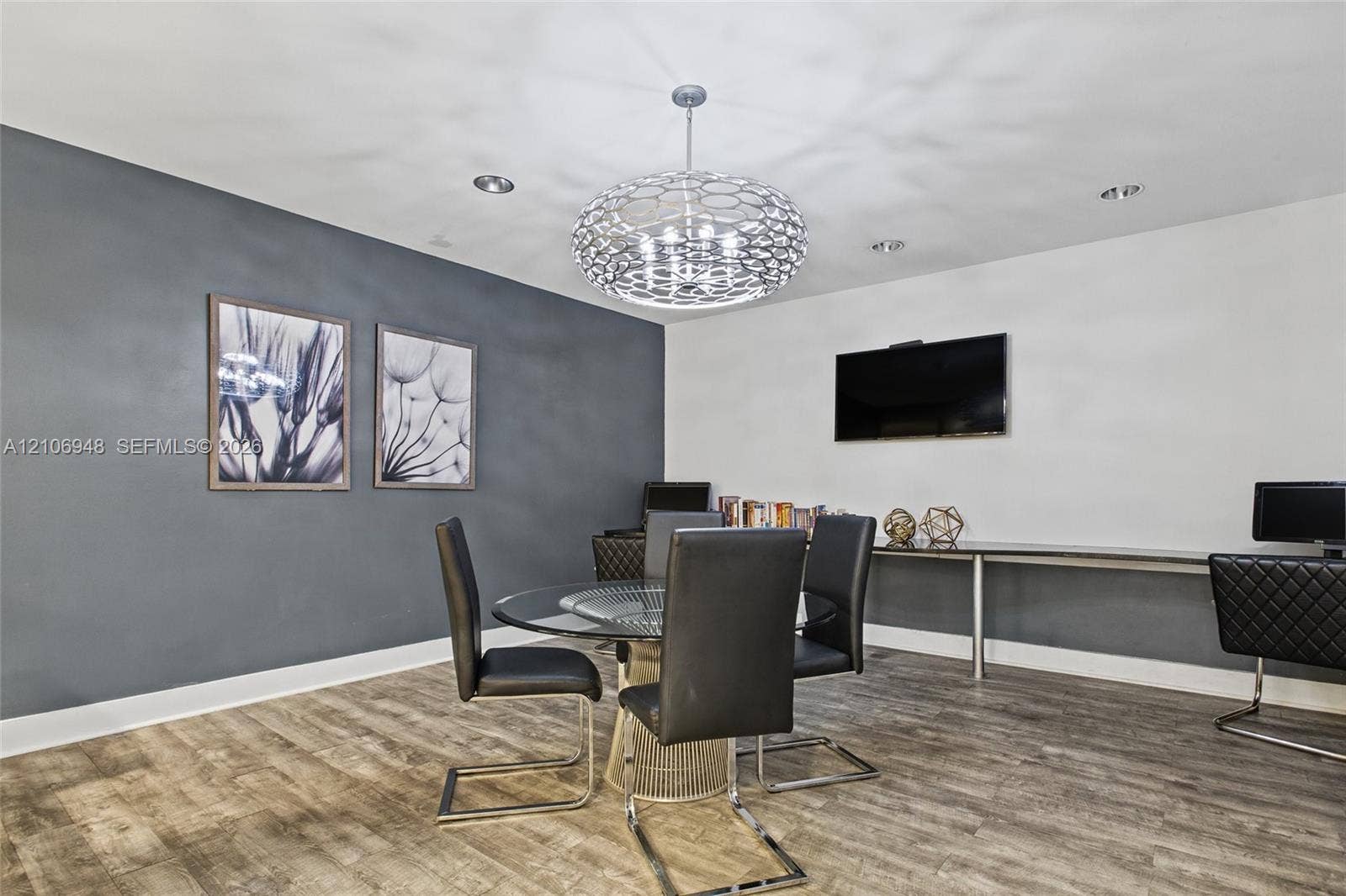 Wood-finish flooring, dark-toned accent wall, recessed lighting, and a modern tiered spherical chandelier