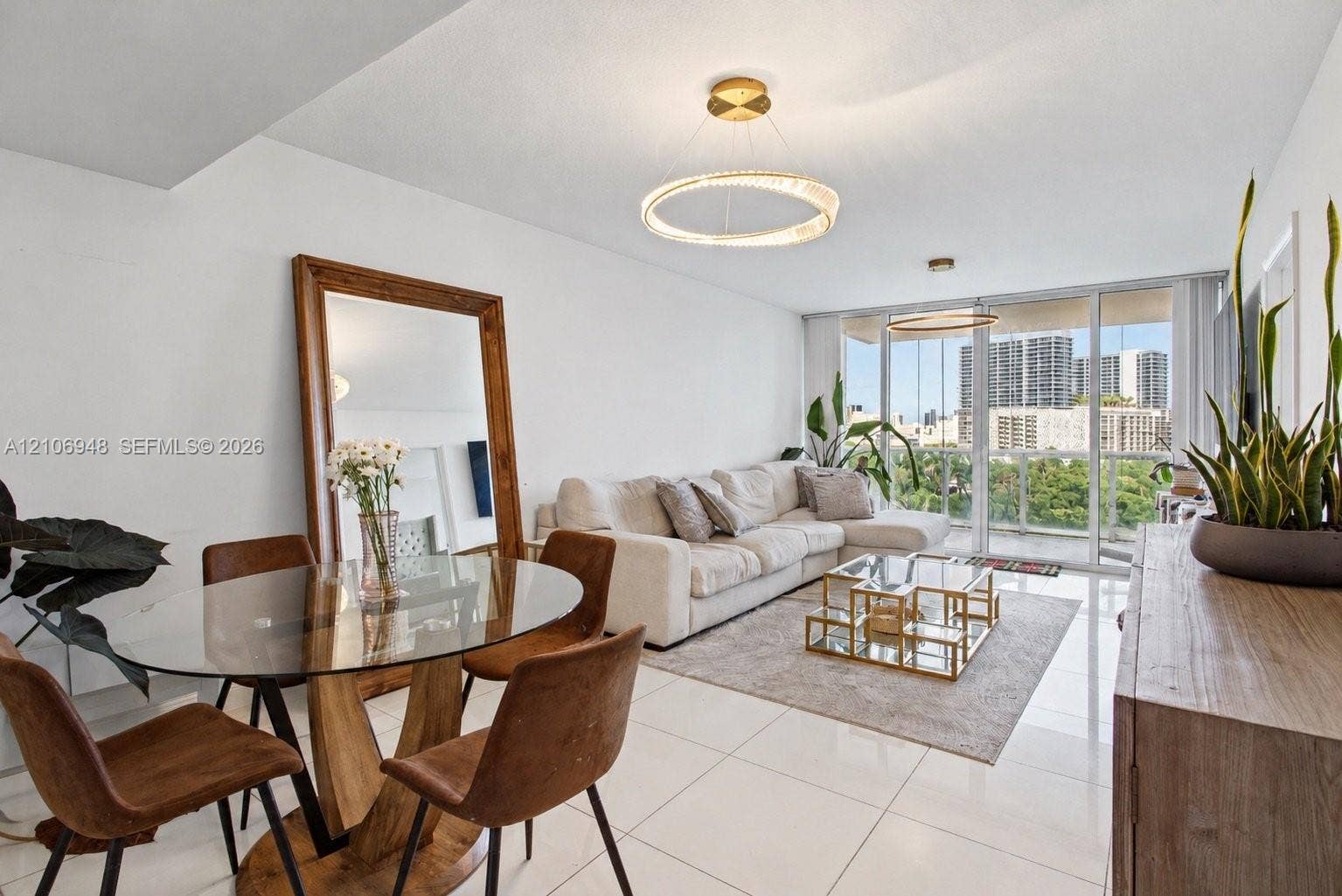 Open-concept space featuring polished tile flooring, contemporary circular LED light fixtures, floor-to-ceiling glass paneling, and an expansive balcony