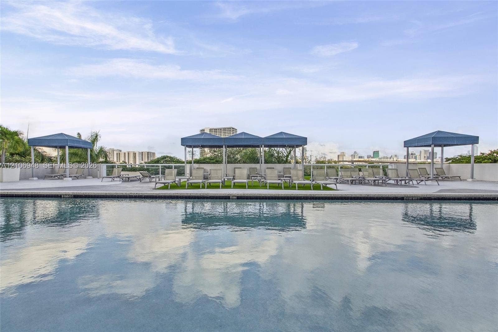 Rooftop swimming pool featuring a concrete deck, glass panel railings, and multiple shaded cabanas
