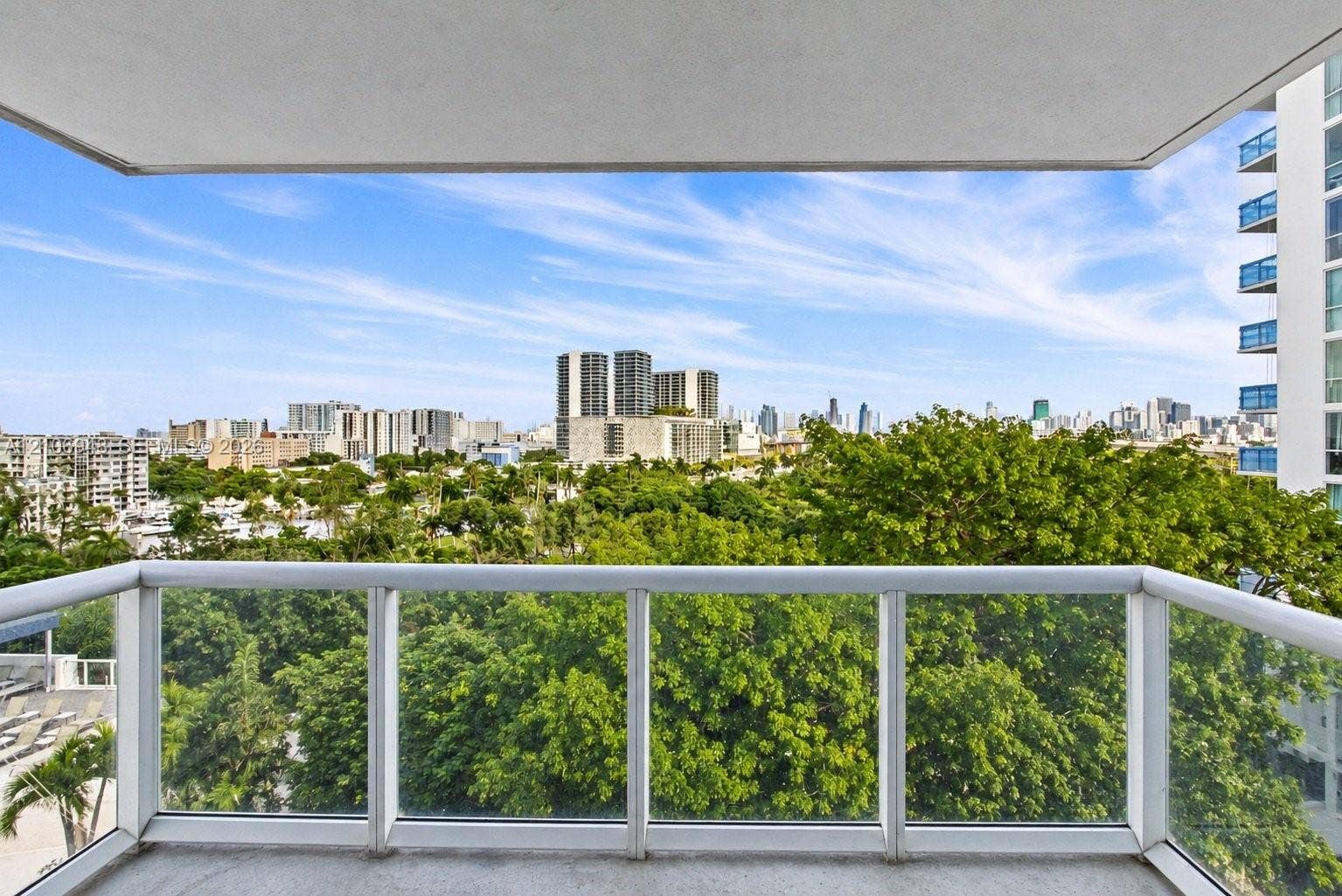 Covered outdoor balcony featuring a glass-panel railing and concrete flooring