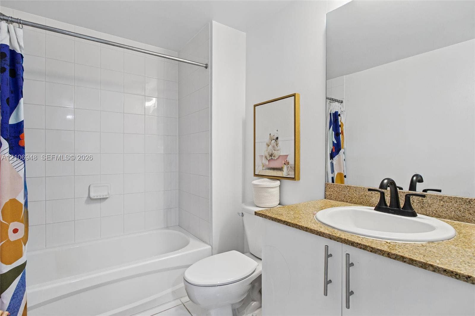 Bathroom featuring a white bathtub, white wall tiling, a vanity with a stone countertop, an integrated oval sink, and a large wall-mounted mirror