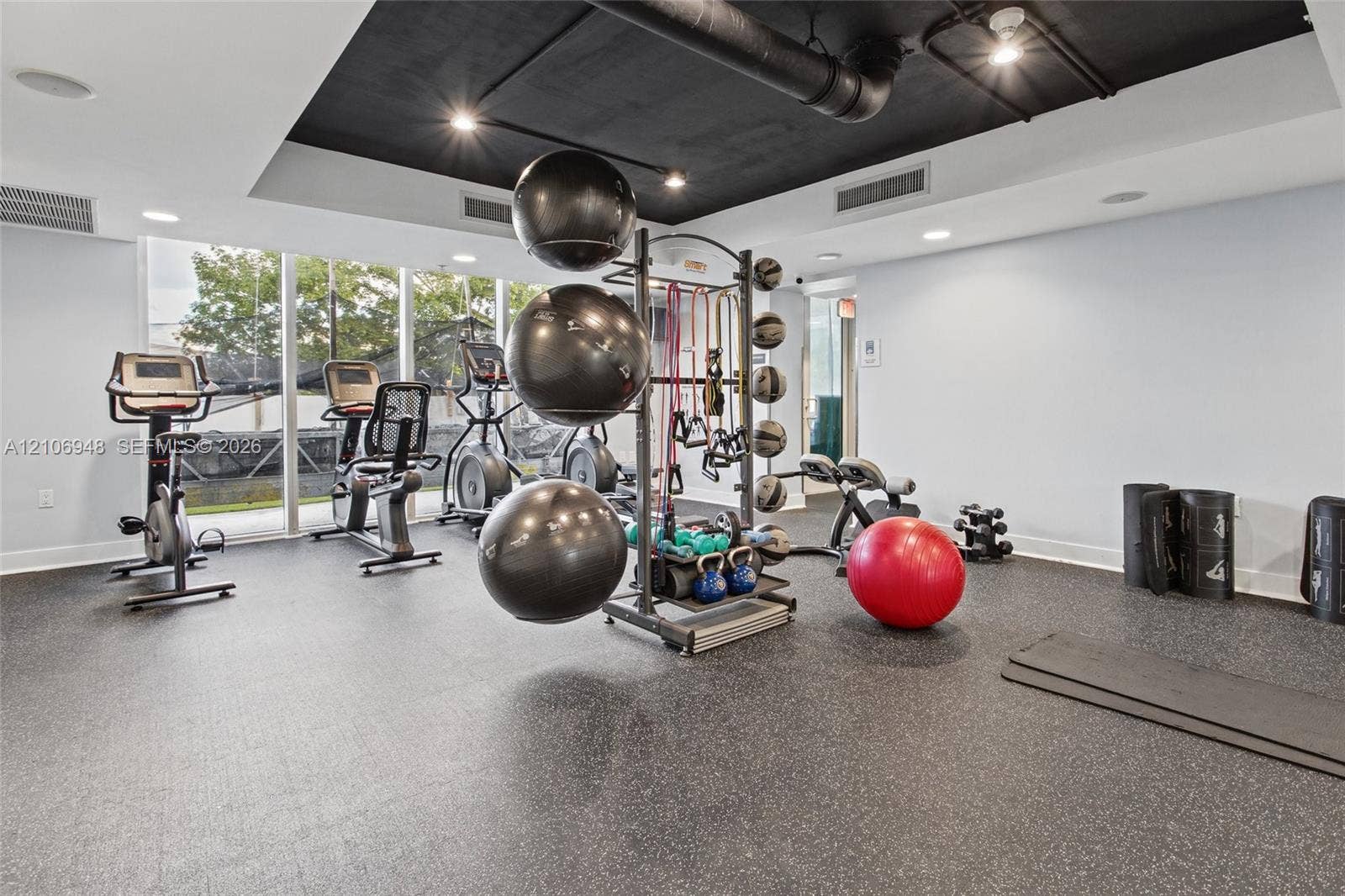 Fitness center featuring rubberized flooring, floor-to-ceiling windows, recessed lighting, and an industrial-style exposed black ceiling
