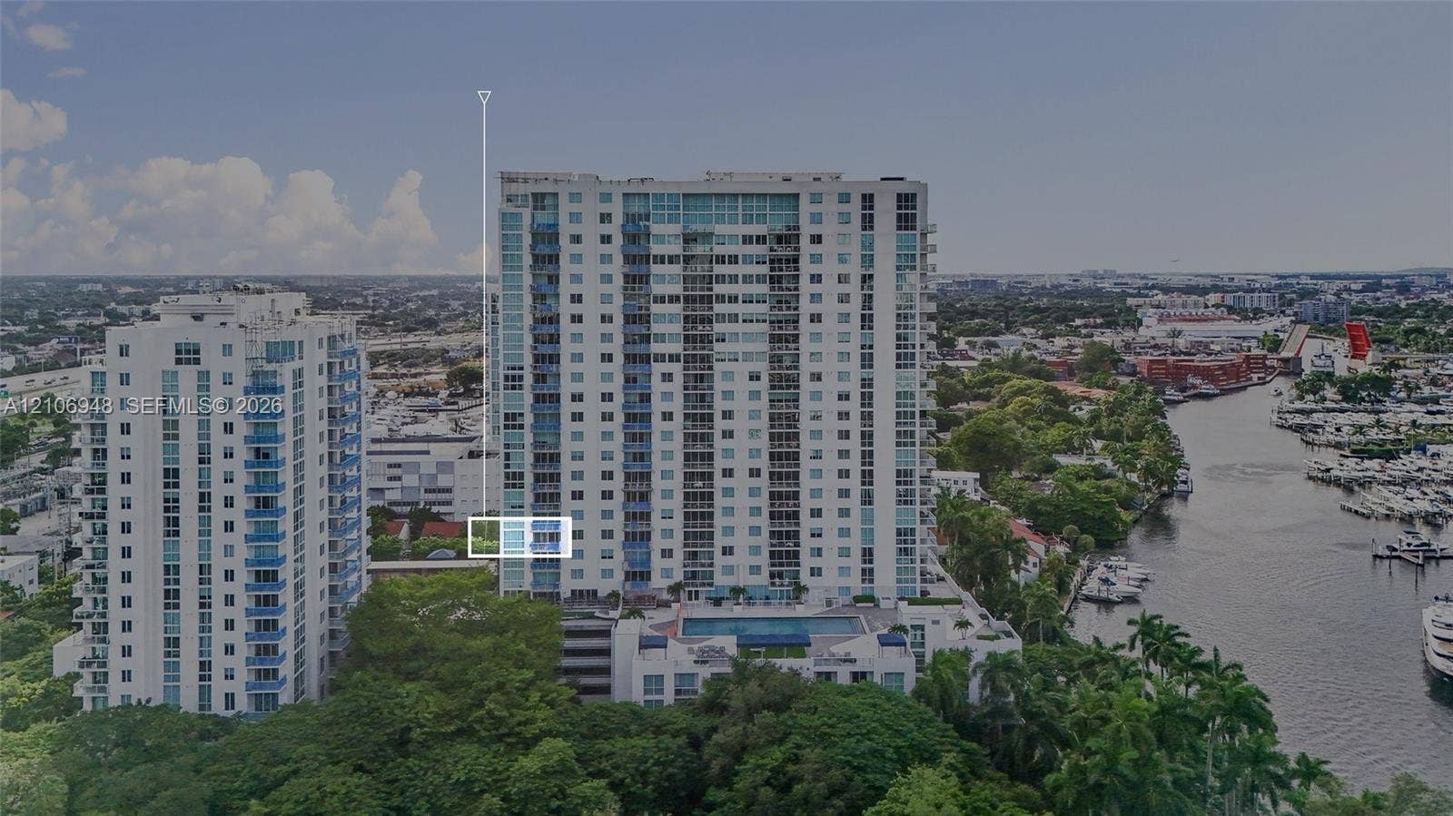 High-rise residential building featuring floor-to-ceiling glass windows, exterior balconies, and an elevated outdoor swimming pool