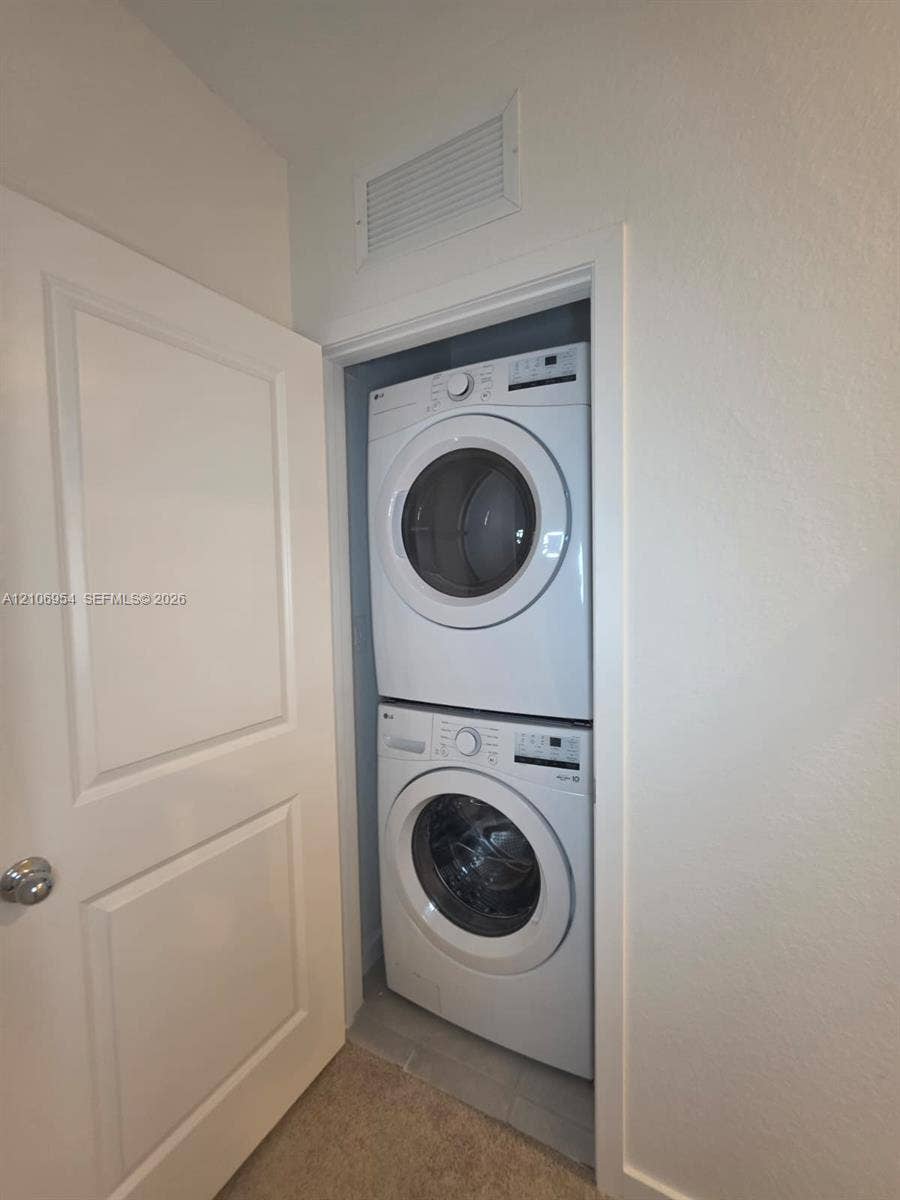 Laundry closet featuring a white stacked washer and dryer unit and a paneled interior door