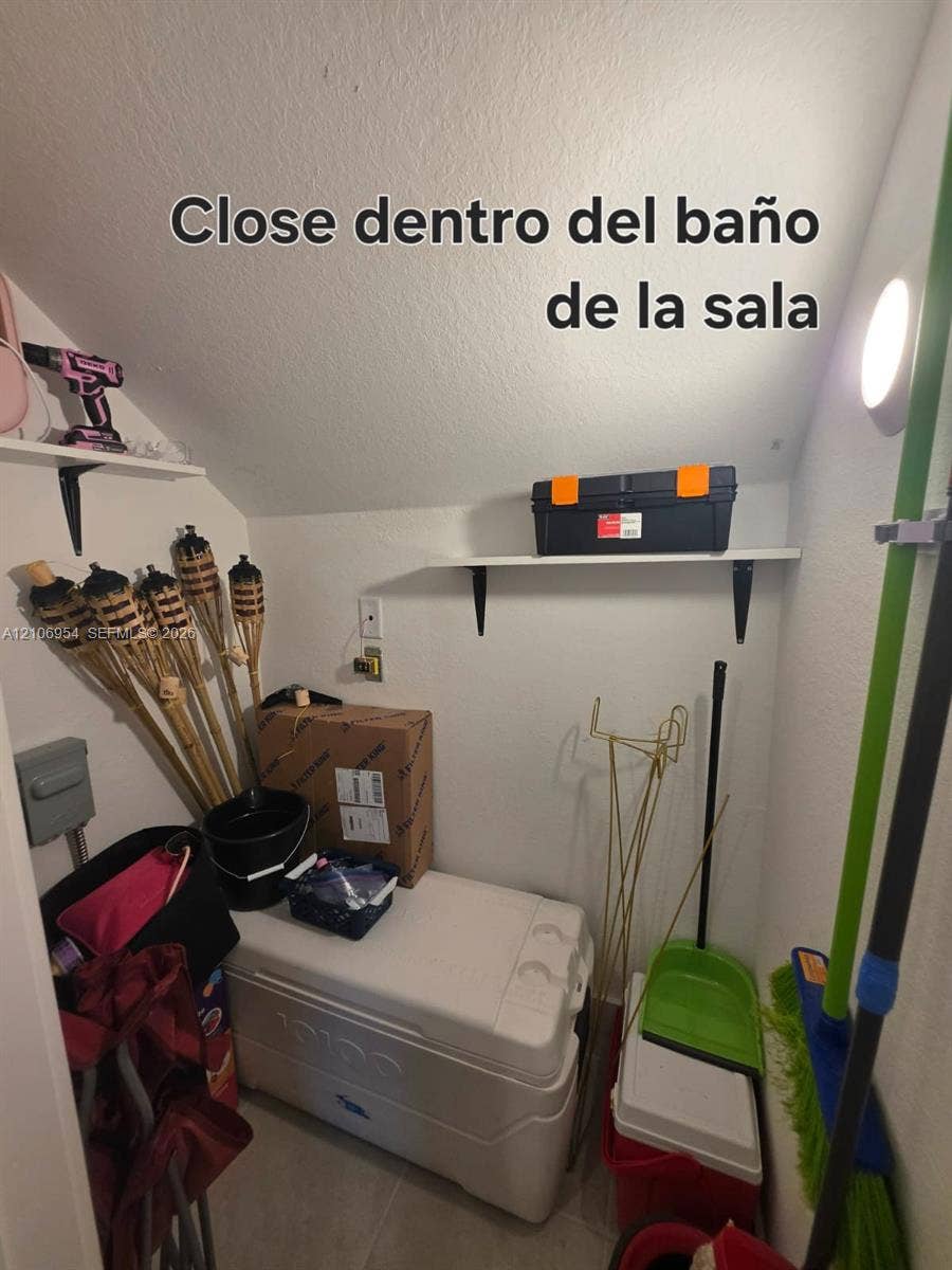Storage closet featuring two wall-mounted shelving units and an integrated electrical outlet