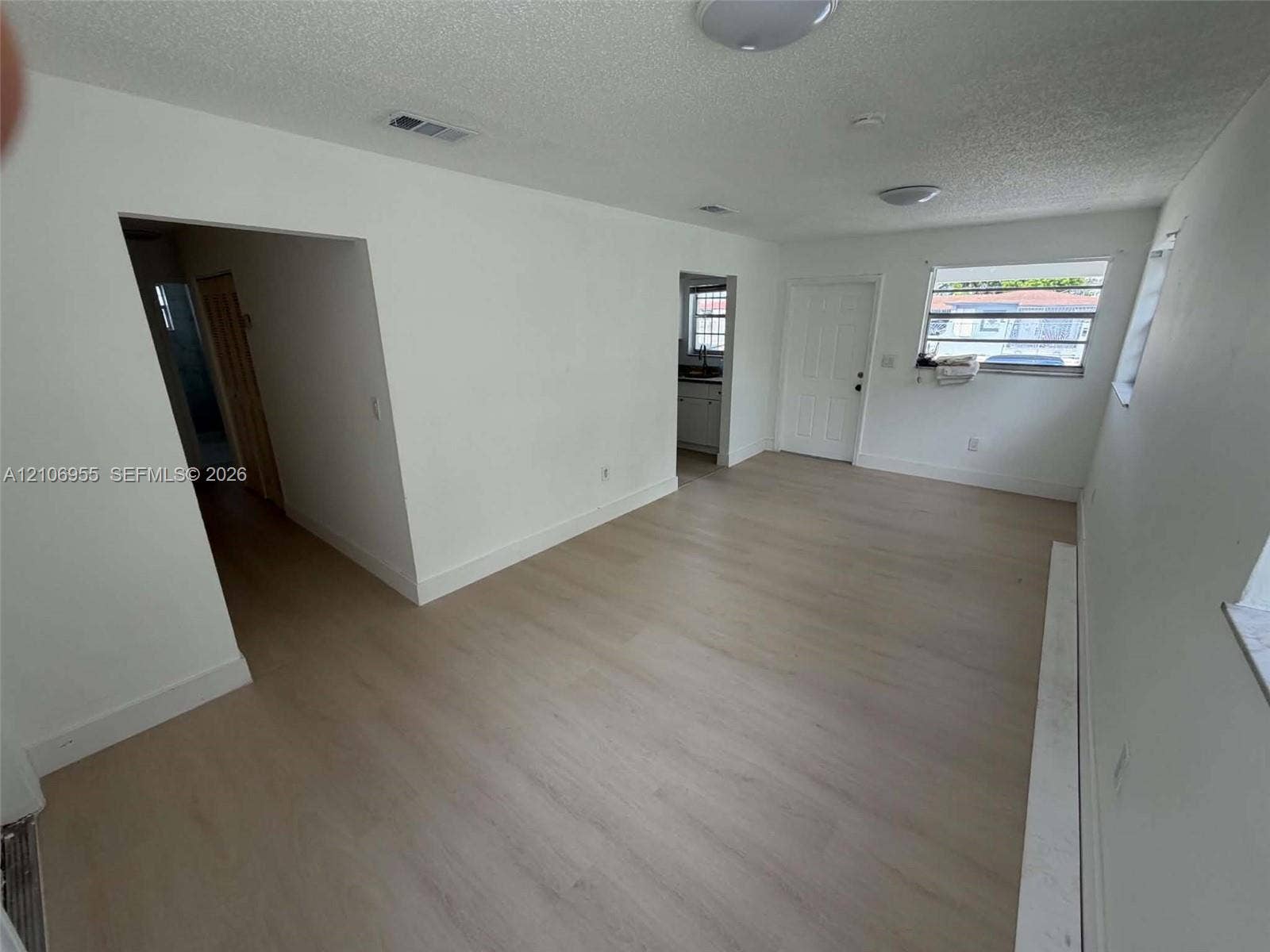 Neutral-toned wood-finish flooring, white wall finishes, flush-mount ceiling lighting, and multi-pane windows