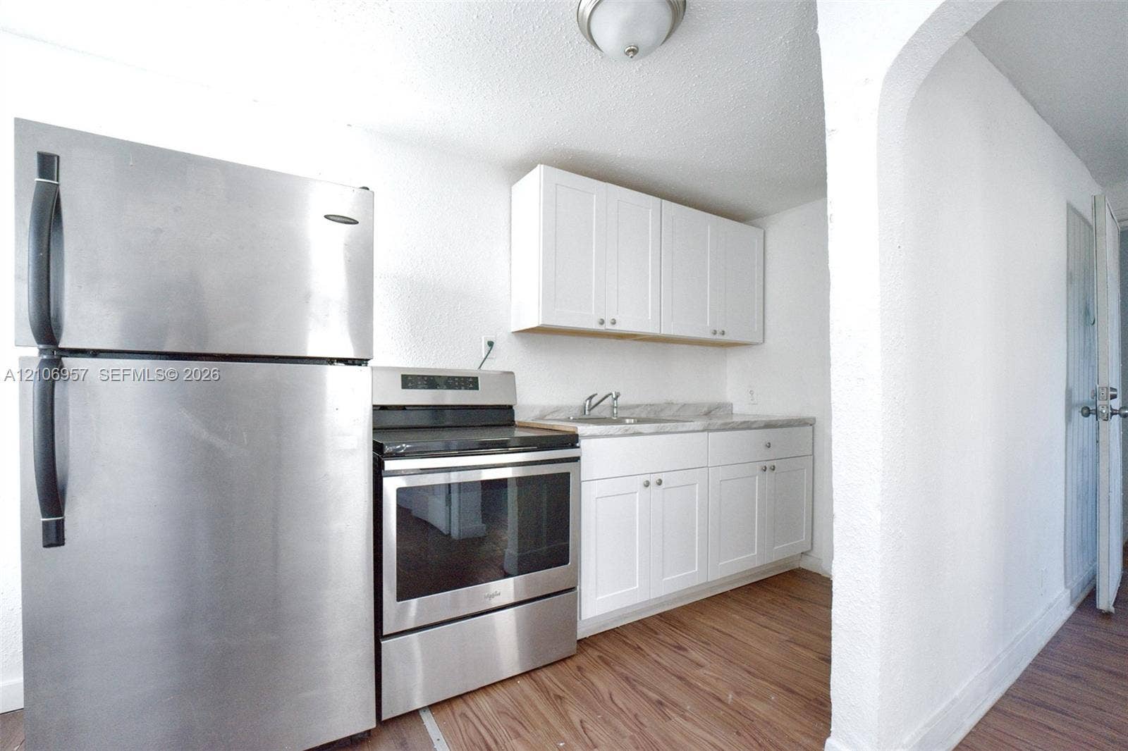 3660 NW 20th Avenue, #4, Miami, Miami, FL 33142 Kitchen featuring white cabinetry, wood-finish flooring, stainless steel refrigerator, stainless steel electric range, and stone-finish countertop