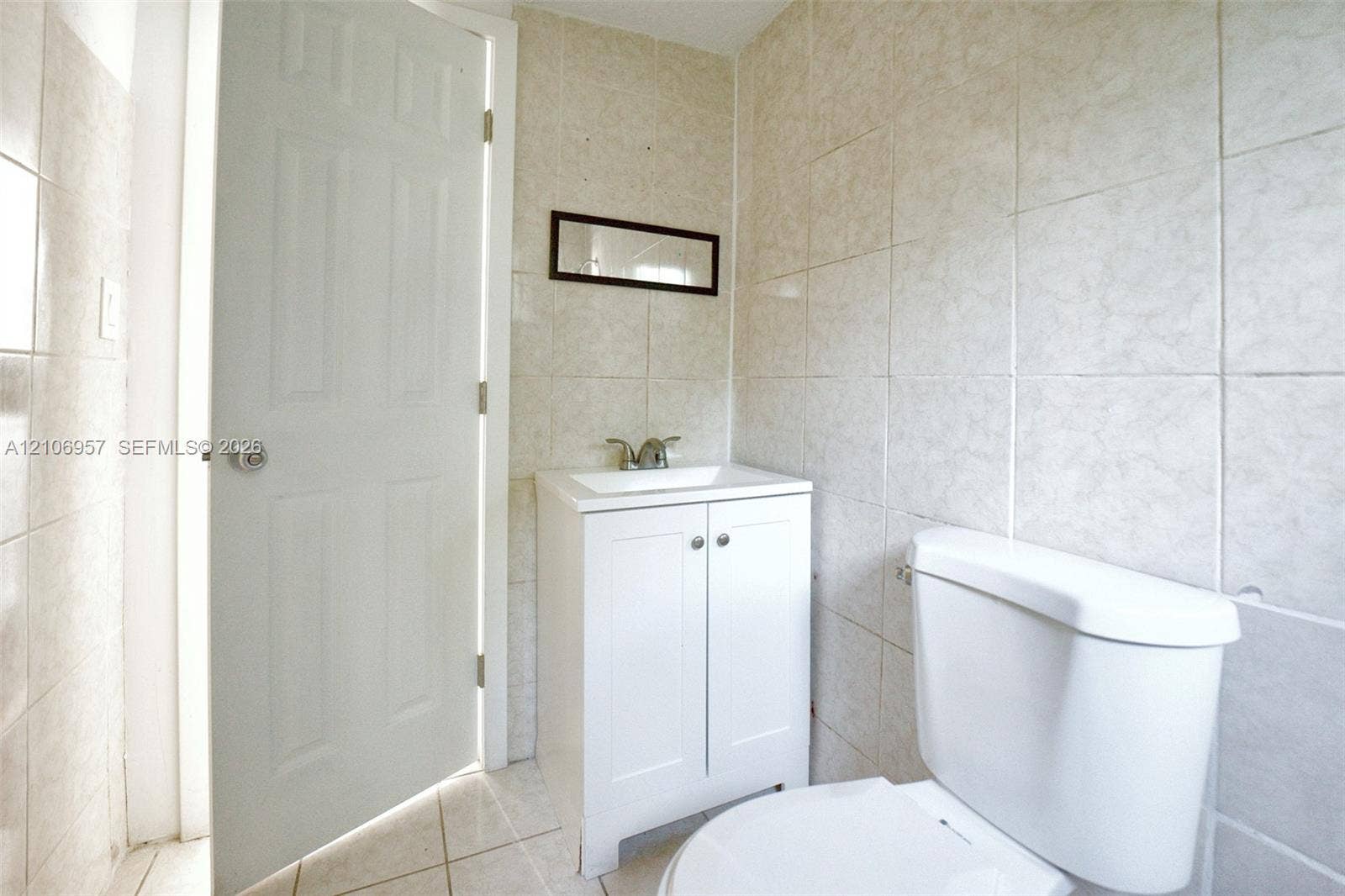 3660 NW 20th Avenue, #4, Miami, Miami, FL 33142 White vanity with a rectangular sink, dual-handle faucet, full-height wall tiling, and tiled flooring