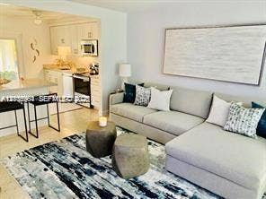 Open-concept interior featuring light-toned flooring, white cabinetry, a breakfast bar with dual-seating capacity, and built-in kitchen appliances