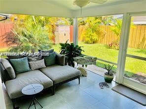 Screened lanai featuring large-format ceramic tile flooring, ceiling fan, and access to a fenced backyard