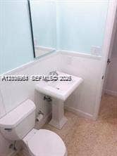 Pedestal sink with chrome faucet, wall-mounted mirror, and tile flooring