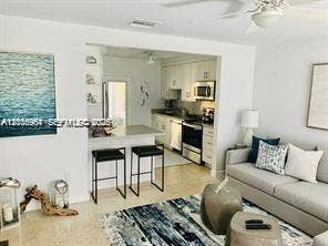 Kitchen featuring white cabinetry, integrated stainless steel appliances, and a breakfast bar