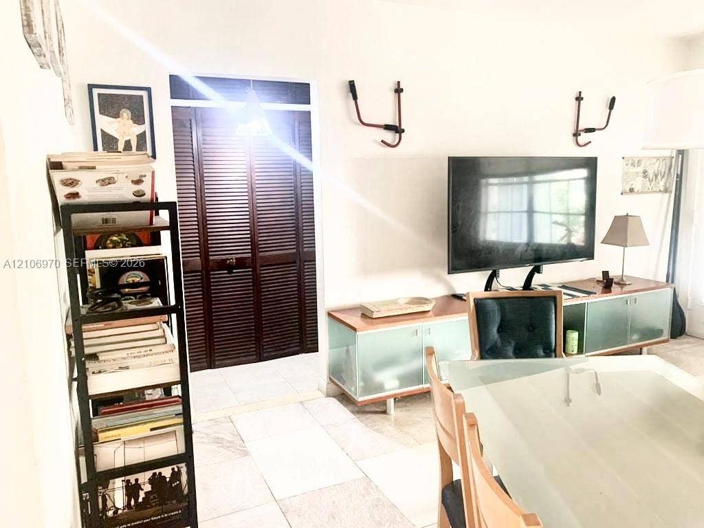 8540 Byron Avenue, #1B, Miami Beach, Miami Beach, FL 33141 Custom built-in cabinetry with frosted glass panels and wood-tone surfacing, paired with dark-stained wood louvered closet doors and neutral tile flooring