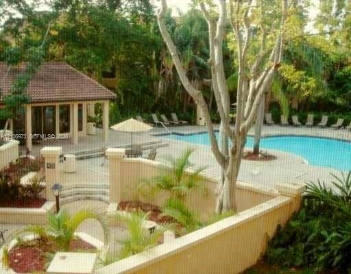 504 Gardens Drive, #101, Pompano Beach, Pompano Beach, FL 33069 Community pool area featuring an in-ground swimming pool, tiered concrete decking, masonry perimeter wall, covered pavilion, and mature landscaping