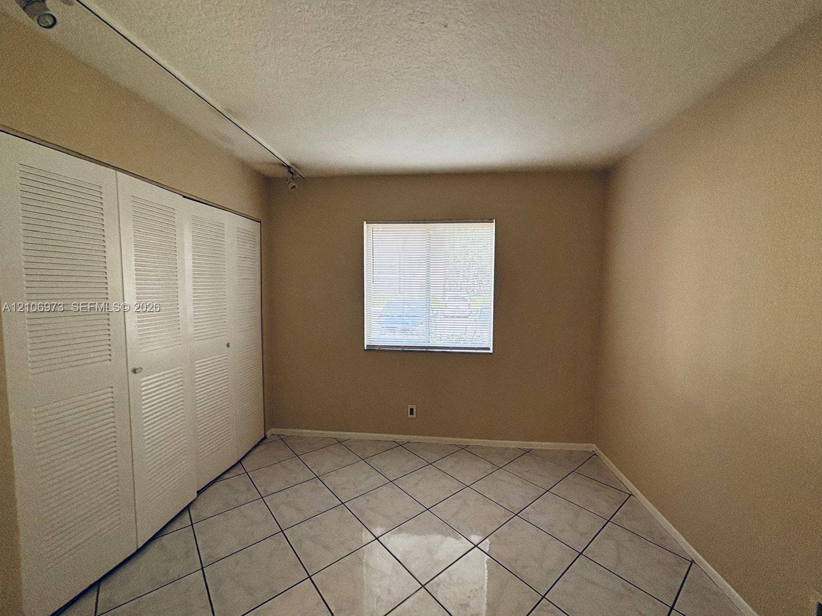 504 Gardens Drive, #101, Pompano Beach, Pompano Beach, FL 33069 Interior room featuring large-format diagonal tile flooring, bi-fold louvered closet doors, and a single-pane window
