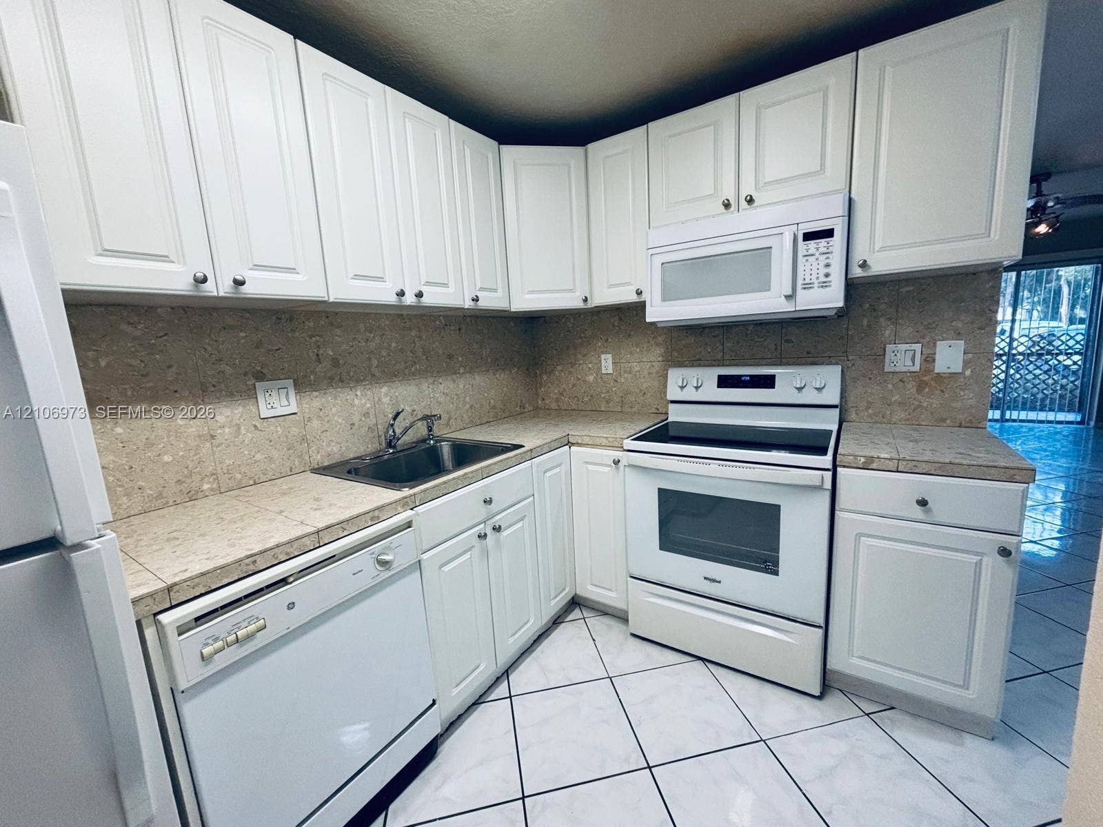 504 Gardens Drive, #101, Pompano Beach, Pompano Beach, FL 33069 Kitchen featuring white cabinetry, tile countertops and backsplash, integrated white appliances, and large-format tile flooring