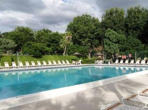 504 Gardens Drive, #101, Pompano Beach, Pompano Beach, FL 33069 Rectangular swimming pool featuring a concrete deck, perimeter fencing, and mature landscaping