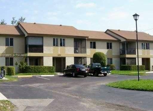 504 Gardens Drive, #101, Pompano Beach, Pompano Beach, FL 33069 Two-story exterior featuring a light-toned stucco faade, shingle roofing, private screened-in balconies, and manicured shrubbery