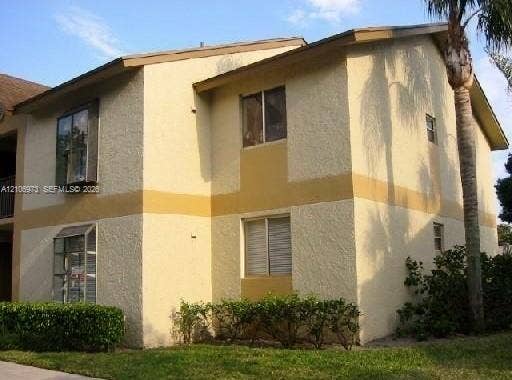 504 Gardens Drive, #101, Pompano Beach, Pompano Beach, FL 33069 Two-story exterior featuring a textured stucco facade, bay windows, and established perimeter shrubbery