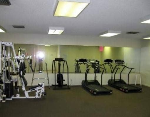 504 Gardens Drive, #101, Pompano Beach, Pompano Beach, FL 33069 Fitness room featuring expansive wall-to-wall mirrors, recessed and flush-mount overhead lighting, and wall-to-wall carpeting
