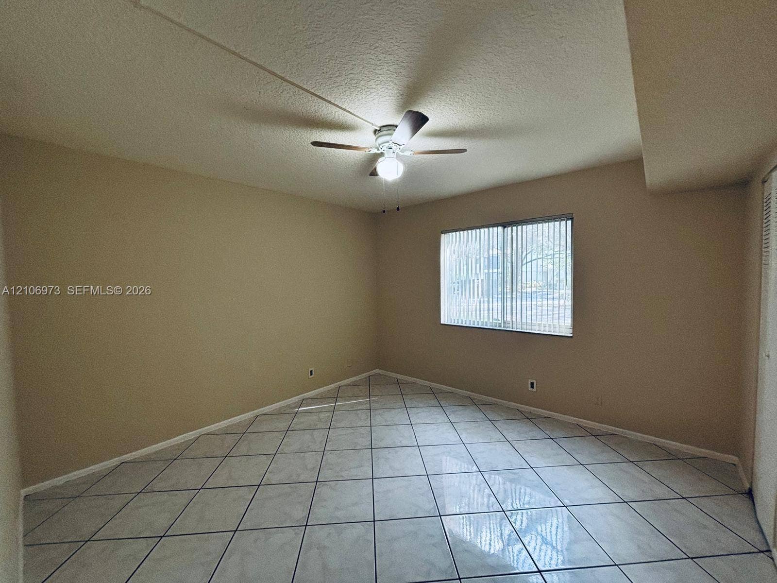 504 Gardens Drive, #101, Pompano Beach, Pompano Beach, FL 33069 Interior space featuring large-format diagonal tile flooring, a multi-blade ceiling fan with integrated lighting, and a window with vertical blinds