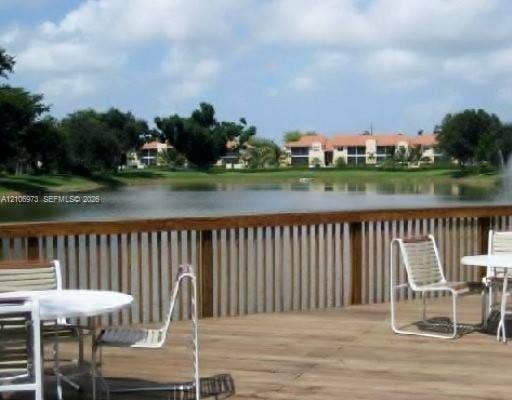 504 Gardens Drive, #101, Pompano Beach, Pompano Beach, FL 33069 Wood-surface deck featuring a horizontal-slat wooden railing overlooking a pond with a water feature