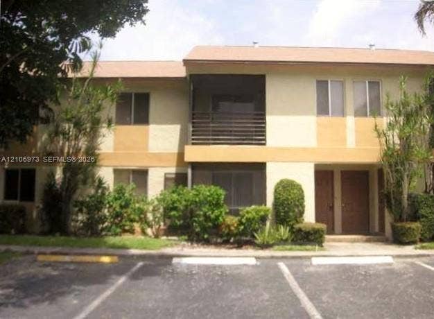 504 Gardens Drive, #101, Pompano Beach, Pompano Beach, FL 33069 Two-story stucco exterior featuring screened balconies, shingled roofing, and paved parking area