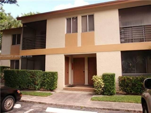 504 Gardens Drive, #101, Pompano Beach, Pompano Beach, FL 33069 Multi-story exterior featuring a stucco facade, screened-in balconies with horizontal railing, and manicured landscaping