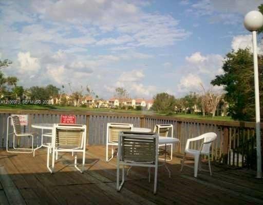 504 Gardens Drive, #101, Pompano Beach, Pompano Beach, FL 33069 Wood-plank deck featuring a vertical-slat perimeter railing, integrated pole lighting, and a water-front location