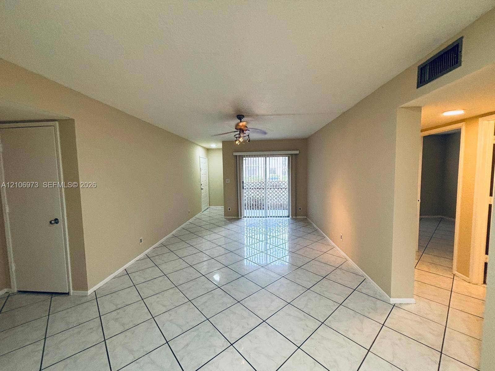 504 Gardens Drive, #101, Pompano Beach, Pompano Beach, FL 33069 Interior space featuring light-toned tile flooring set on a diagonal, sliding glass patio door, and a ceiling fan with integrated lighting