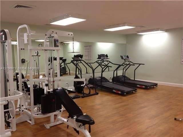 504 Gardens Drive, #101, Pompano Beach, Pompano Beach, FL 33069 Fitness room featuring wood-finish flooring, wall-to-wall mirrors, and flush-mount lighting fixtures