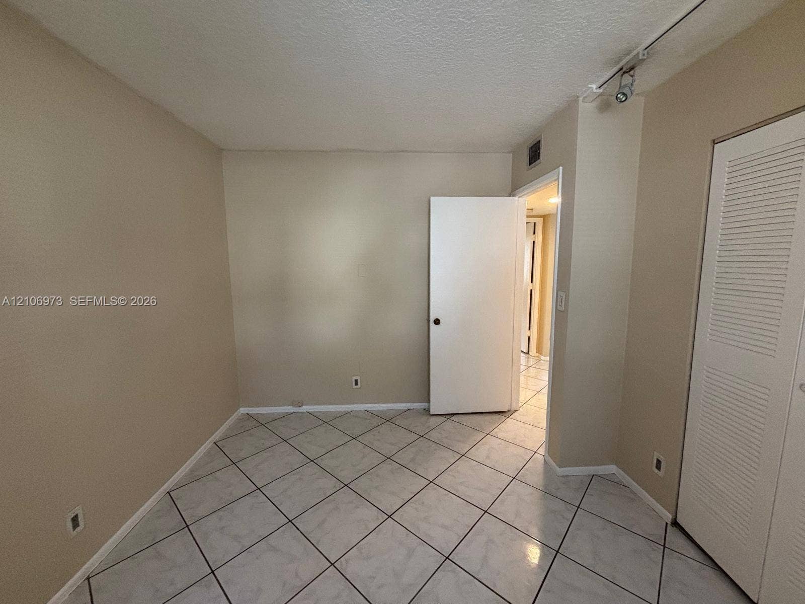 504 Gardens Drive, #101, Pompano Beach, Pompano Beach, FL 33069 Interior room featuring large-format diagonal tile flooring, built-in louvered closet doors, and adjustable track lighting