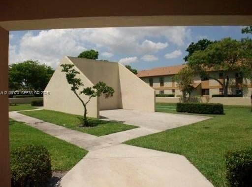 504 Gardens Drive, #101, Pompano Beach, Pompano Beach, FL 33069 Recreational handball court featuring a smooth concrete pad and stucco-finished walls, set within a landscaped area with concrete walkways and manicured hedges