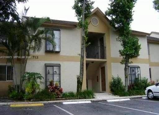 504 Gardens Drive, #101, Pompano Beach, Pompano Beach, FL 33069 Two-story stucco exterior featuring a gable roofline, upper-level balcony with metal railing, and multi-pane windows