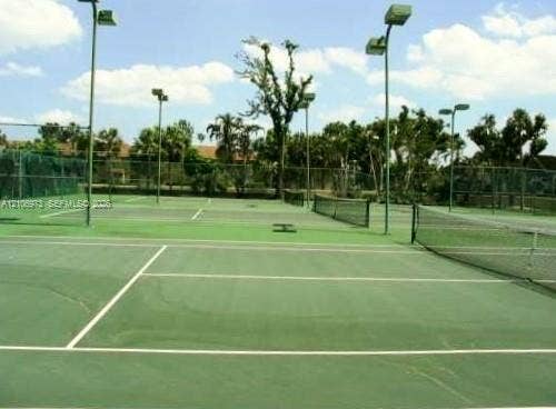 504 Gardens Drive, #101, Pompano Beach, Pompano Beach, FL 33069 Tennis court featuring a paved surface, perimeter chain-link fencing, and overhead court lighting