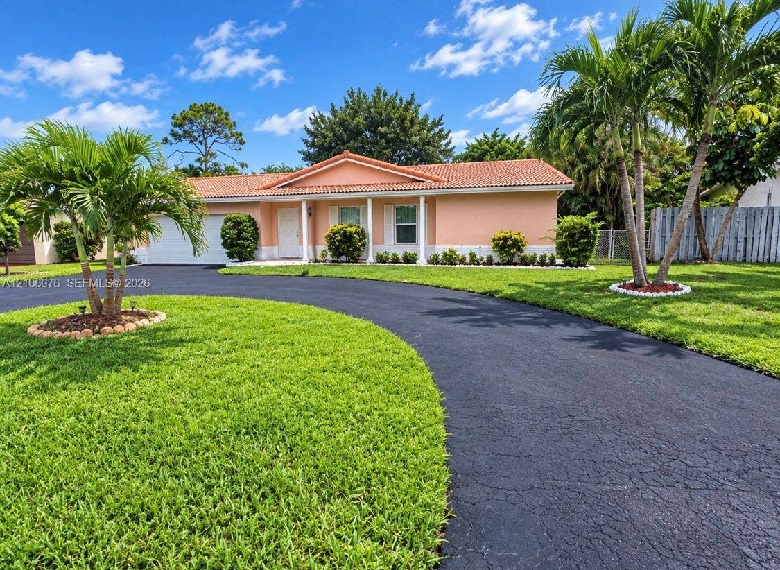 8376 NW 16th Street, Coral Springs, Coral Springs, FL 33071 Single-story residence featuring a tile roof, covered front entrance with structural columns, and an expansive paved circular driveway situated on a landscaped lot with palm trees