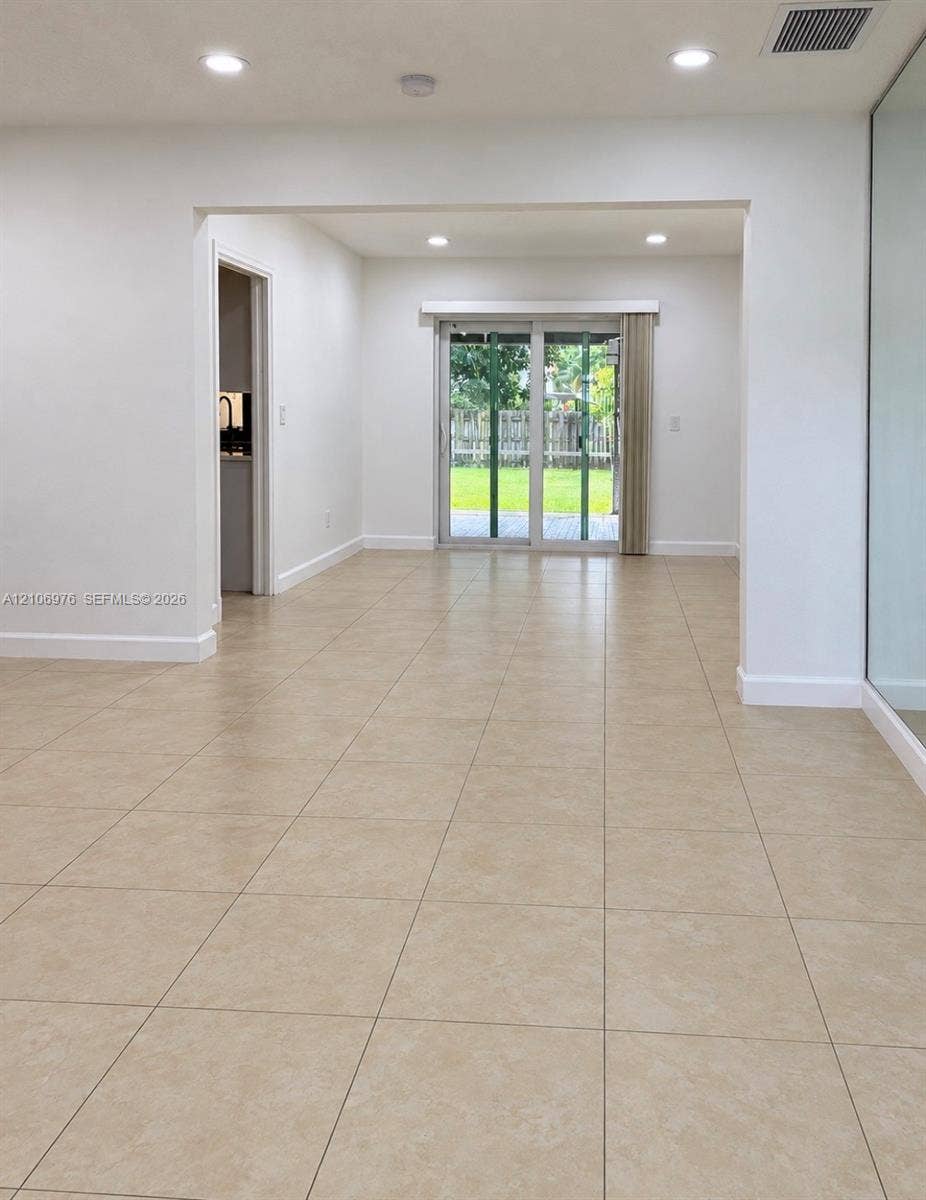8376 NW 16th Street, Coral Springs, Coral Springs, FL 33071 Neutral ceramic tile flooring, recessed lighting, and sliding glass doors leading to a paved patio