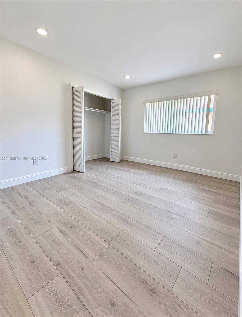 8376 NW 16th Street, Coral Springs, Coral Springs, FL 33071 Neutral-toned wood-finish flooring, recessed lighting, and a closet with louvered bi-fold doors