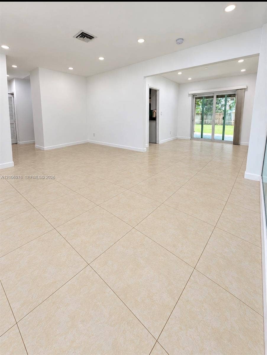 8376 NW 16th Street, Coral Springs, Coral Springs, FL 33071 Open interior featuring large-format neutral tile flooring, recessed ceiling lighting, and sliding glass doors
