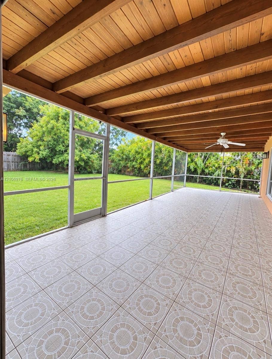 8376 NW 16th Street, Coral Springs, Coral Springs, FL 33071 Screened-in patio featuring decorative tile flooring, exposed wood-beam ceiling, ceiling fan, and lawn access
