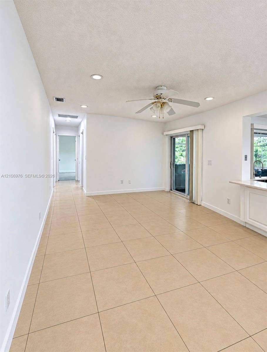 8376 NW 16th Street, Coral Springs, Coral Springs, FL 33071 Neutral-toned tile flooring, recessed ceiling lighting, a white ceiling fan with integrated light fixture, and a sliding glass door providing external access