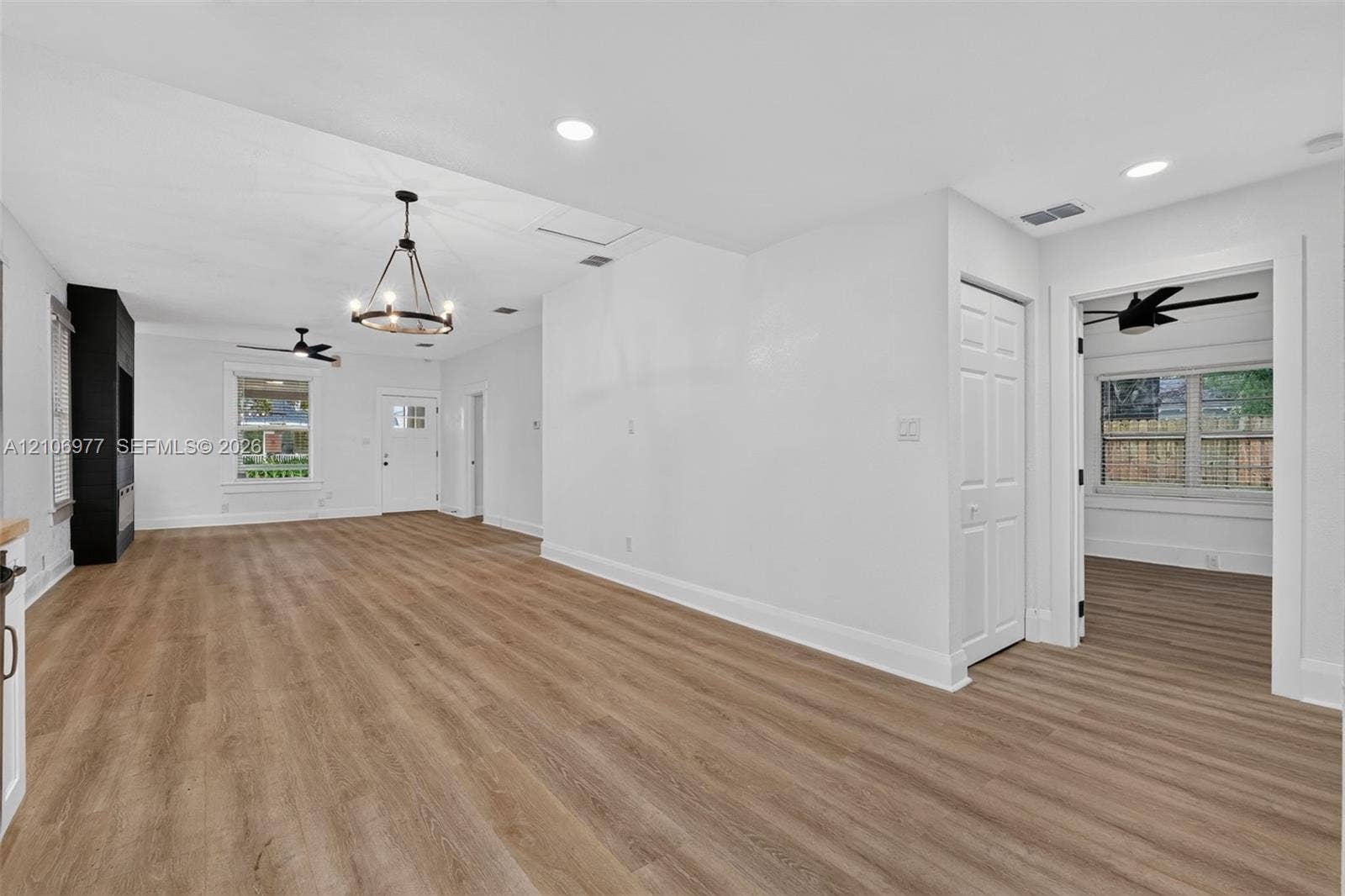 Open-concept interior featuring wood-finish flooring, recessed lighting, a modern chandelier, and built-in black cabinetry