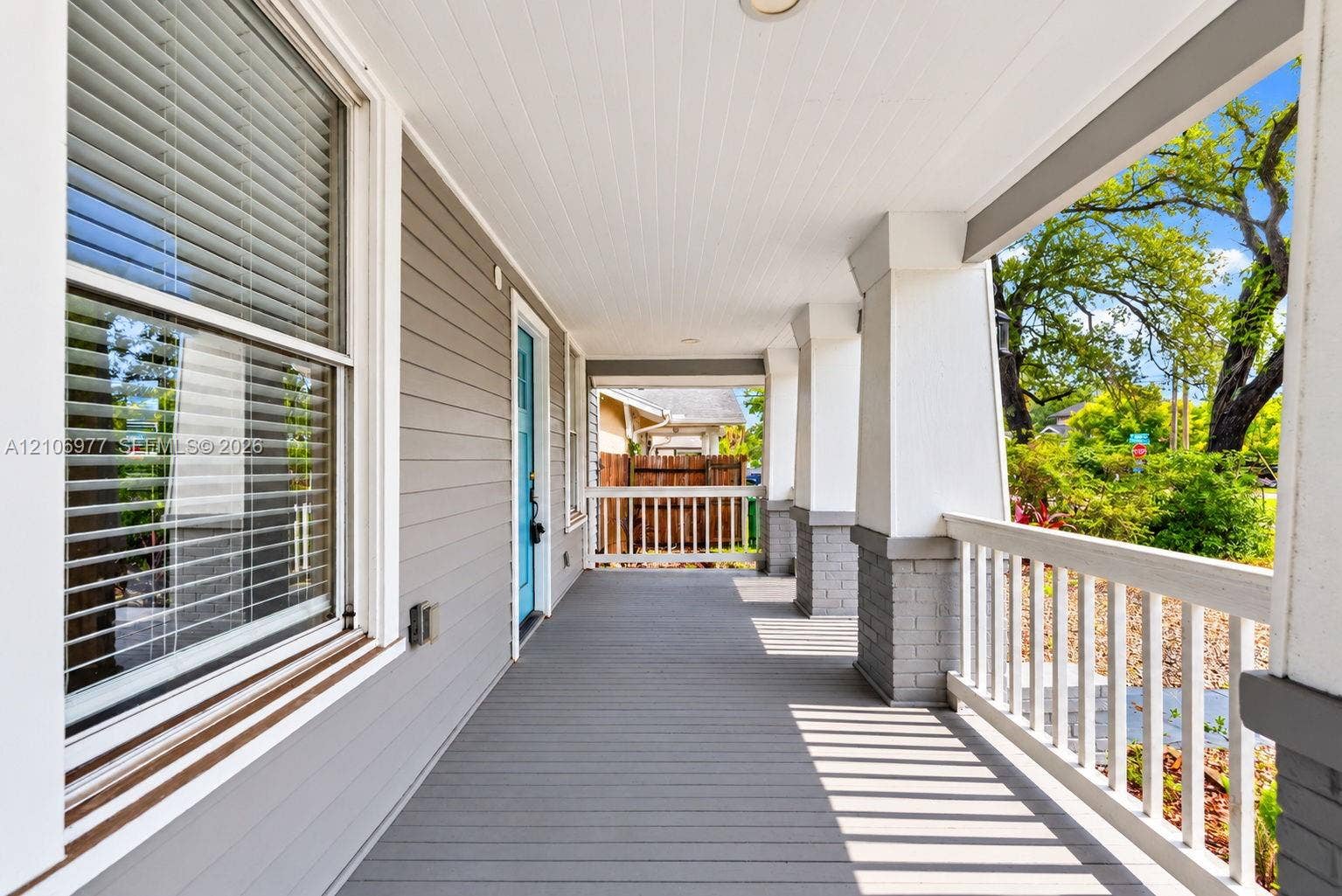Covered front porch featuring tapered columns on brick piers, horizontal siding, and white railing
