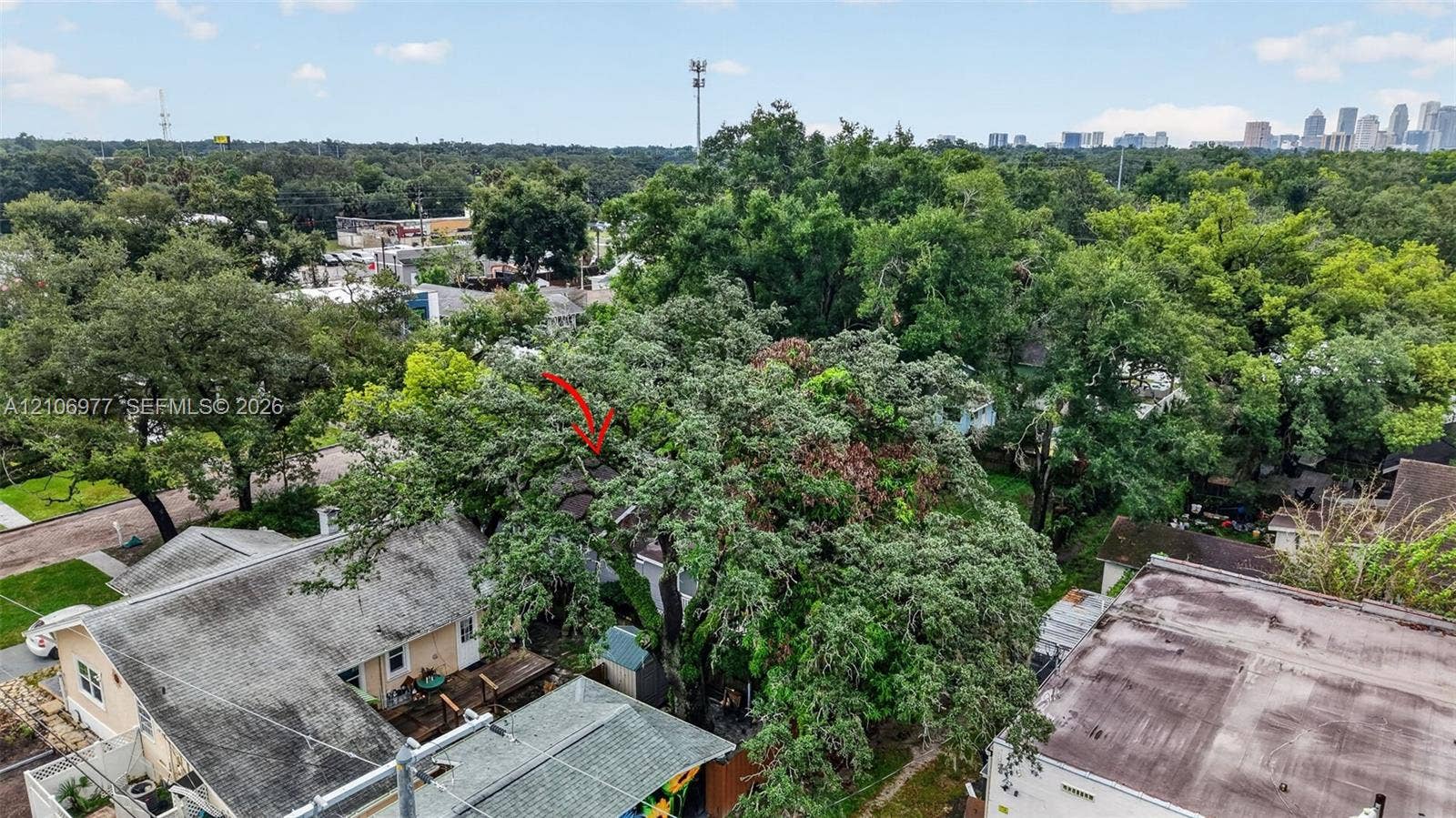 Aerial perspective featuring a multi-structure property with pitched shingled roofs and mature tree canopy