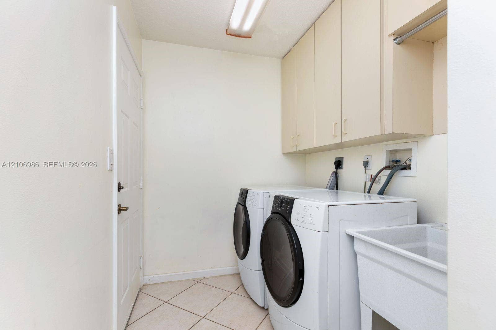 3801 SW 147th Avenue, Miramar, FL 33027 Laundry area featuring built-in upper cabinetry, utility sink, tile flooring, and overhead lighting